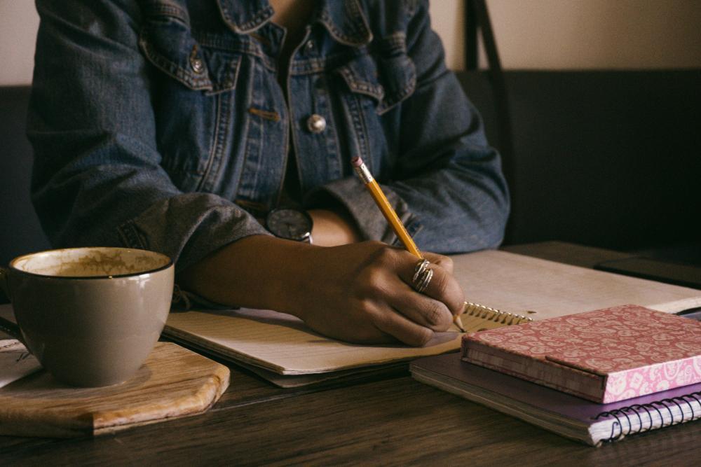 Decoratieve foto van een vrouw die in een schrift schrijft.