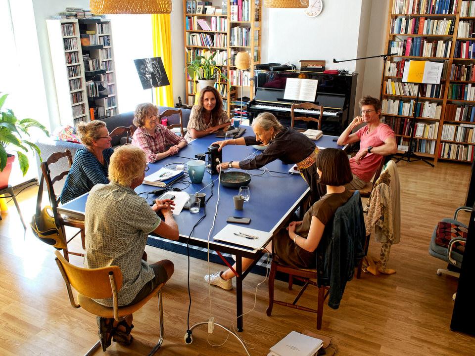 Foto van een eerdere workshop. Een groep deelnemers zit lachend rond een tafel.