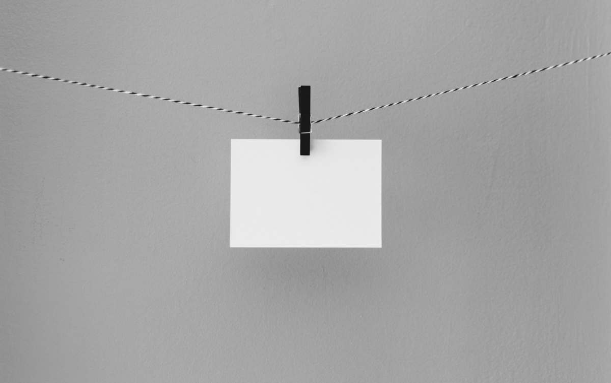 Decoratieve afbeelding van een velletje papier dat aan een zwarte wasknijper aan een waslijn hangt.
