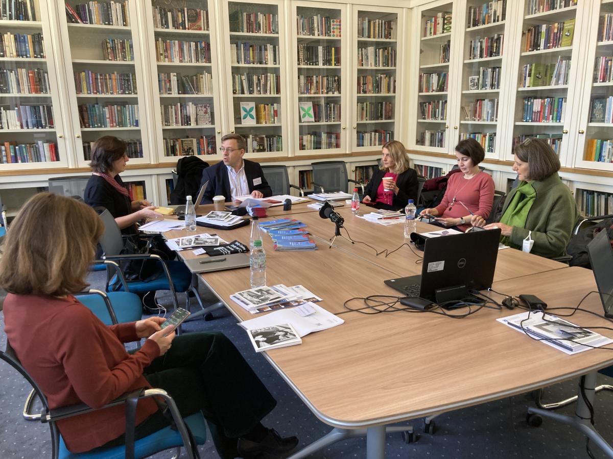 Zes deelnemers aan een ronde tafel voor aanvang van de bijeenkomst.