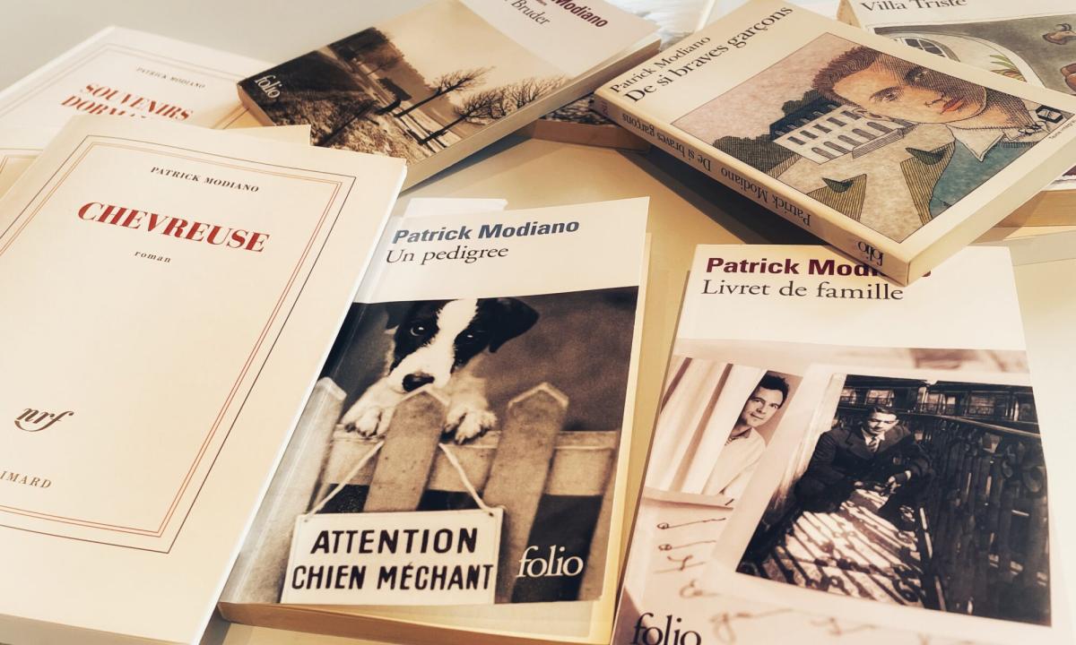 Verschillende werken van Patrick Modiano ongeordend naast en op elkaar op tafel.