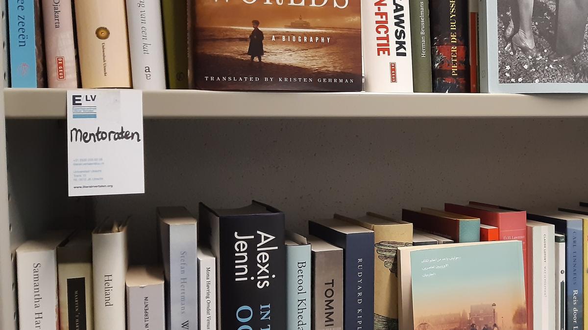 Foto van de boekenkast van het ELV met een briefje met daarop 'Mentoraten'.