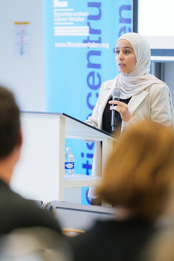 Nour el Houda Ghazlane spreekt voor een groep mensen tijdens de Wetenschappelijke Studiemiddag van het ELV