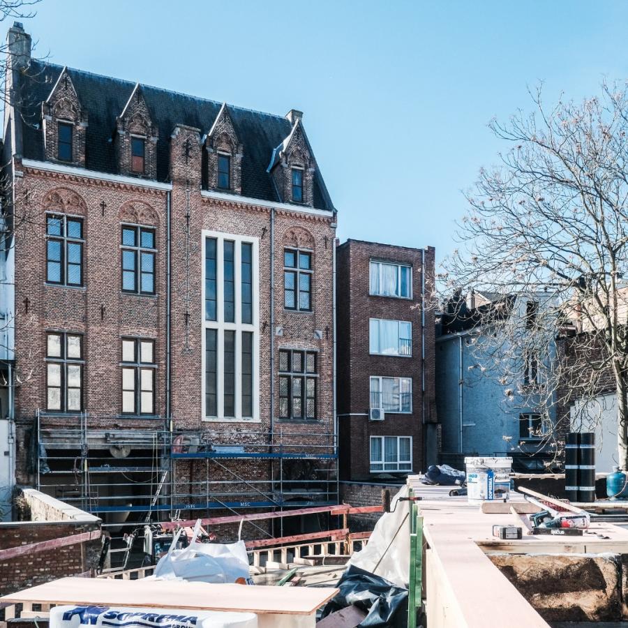 Foto van Hotel Dumont op een zonnige dag. Op de voorgrond liggen bouwmaterialen.